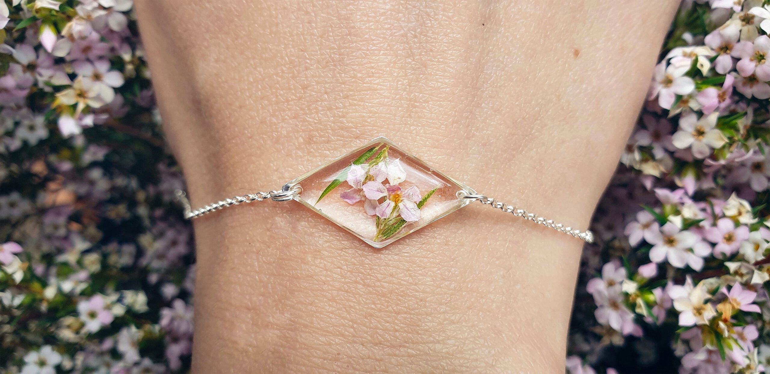 Dettaglio di un bracciale fatto a mano con fiori veri inglobati in resina trasparente su fondo chiaro