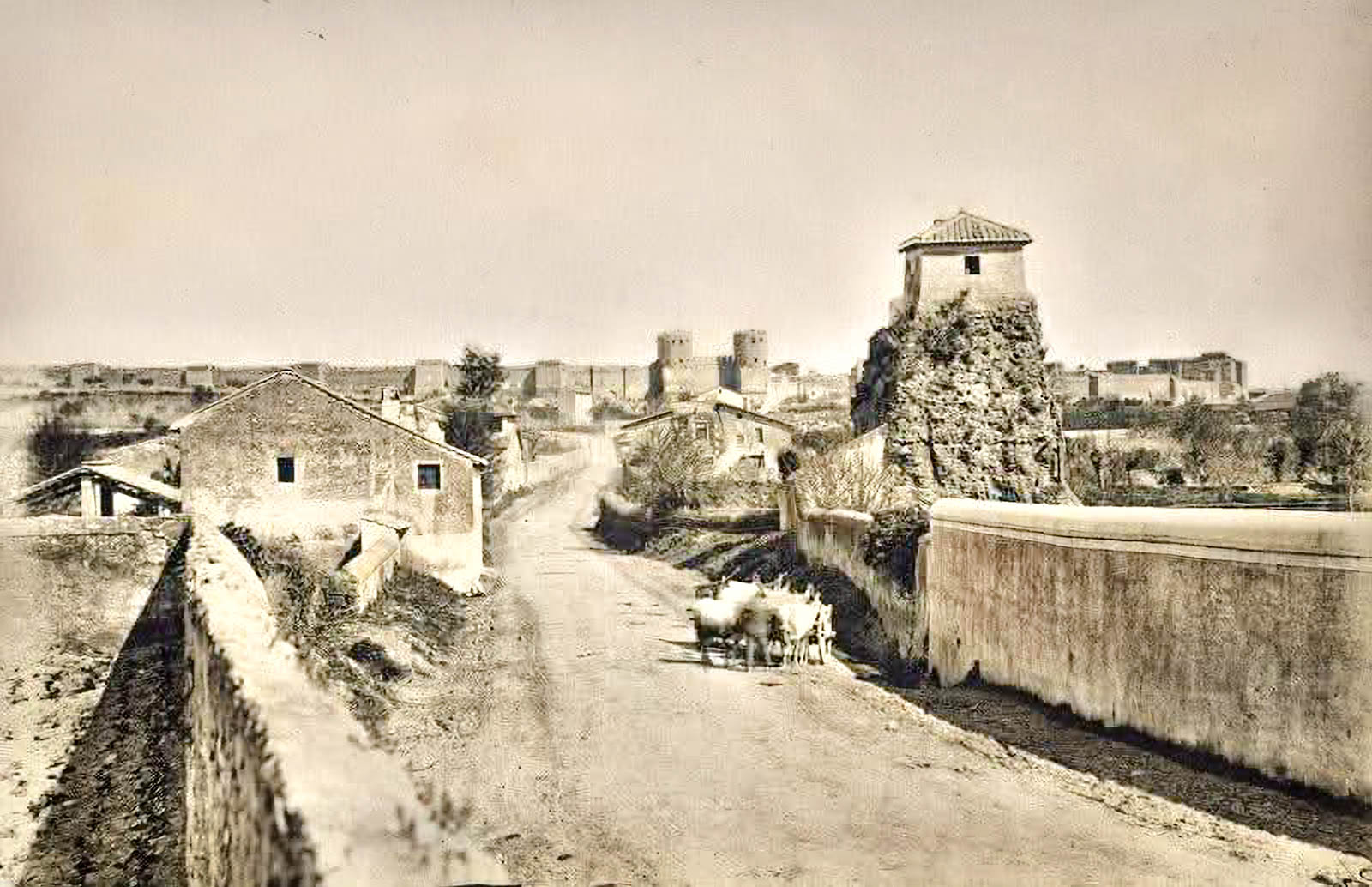 Fotografia d’epoca della via Appia Antica con un carro trainato da buoi, mura e torri sullo sfondo